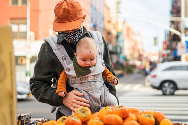 Padre con bambina che compra cachi per strada in città durante l'epidemia di coronavirus — Foto stock