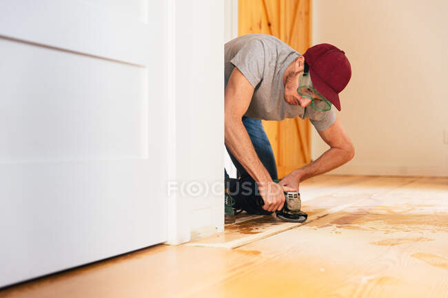 Hombre adulto medio instalando piso de madera en casa - foto de stock