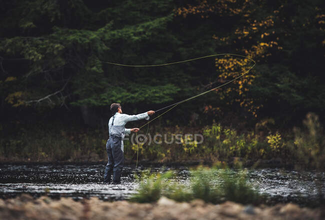 Maschio pescatore getta nel fiume con sfondo scuro in autunno — Foto stock