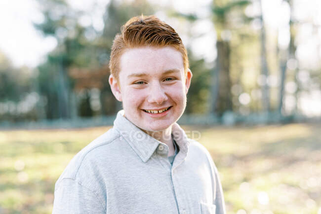 Portrait de jeune garçon roux aux yeux bleus et aux taches de rousseur souriant — Photo de stock
