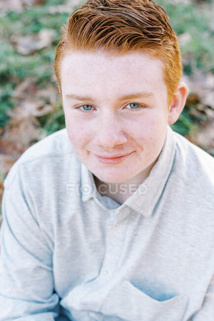 Portrait de jeune garçon roux aux yeux bleus et aux taches de rousseur souriant — Photo de stock