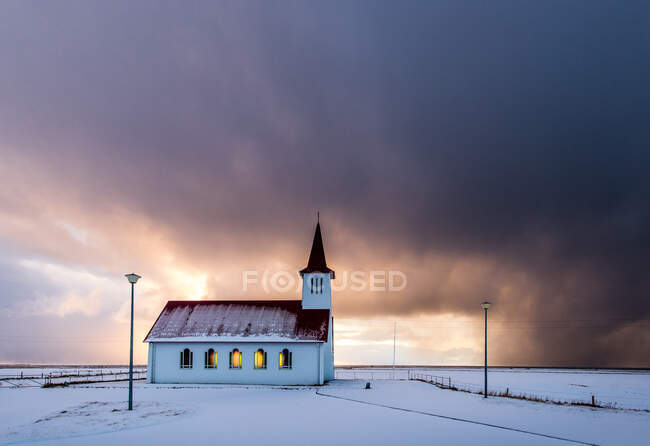 Kirche und dramatischer bewölkter Himmel in verschneiter Landschaft, Island — Stockfoto