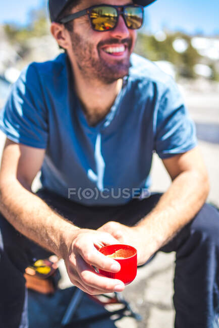 Чоловік посміхається і п'є еспресо від портативного виробника еспресо — стокове фото