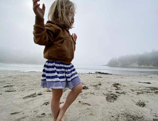 Una giovane ragazza gioca sulla spiaggia sulla costa dell'Oregon in una giornata nebbiosa. — Foto stock