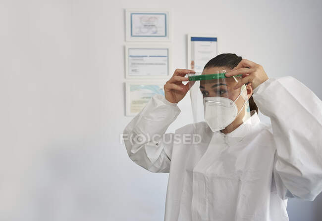 Porträt einer Physiotherapeutin in ihrer Klinik. Der Arzt zieht Schutzkleidung gegen Coronaviren an. — Stockfoto