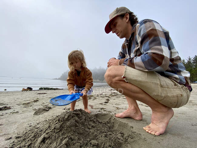 Um pai e uma filha brincam na areia na costa de OR. — Fotografia de Stock