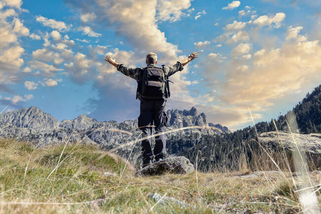 Turista caucásico de mediana edad abre sus brazos y disfruta de la magnífica vista de los Pirineos españoles - foto de stock