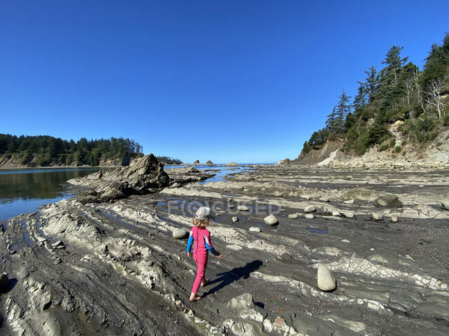 Una giovane ragazza cammina sulla riva con la bassa marea sulla costa dell'Oregon. — Foto stock