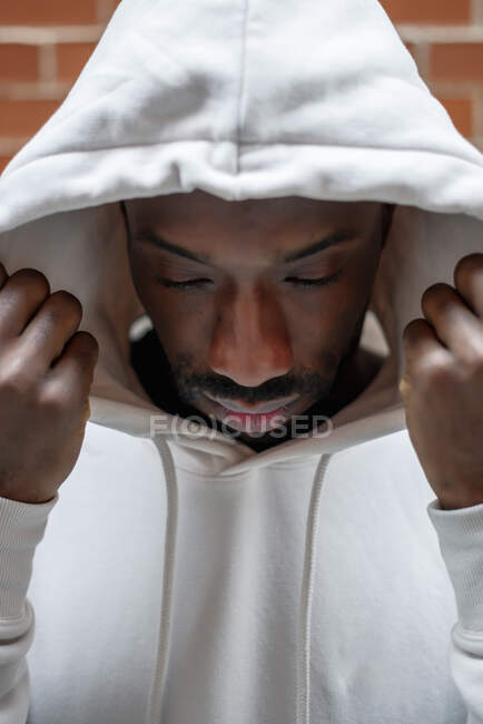 Передняя фотография африканца с серьезным жестом, покрывающим голову белым капюшоном — стоковое фото