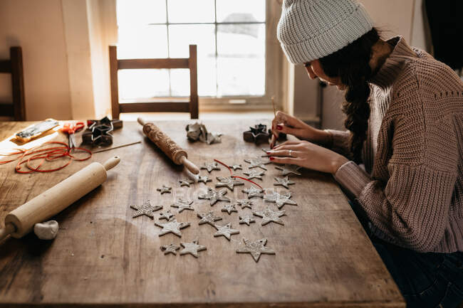 Young woman creating Christmas star ornaments with clay — Stock Photo