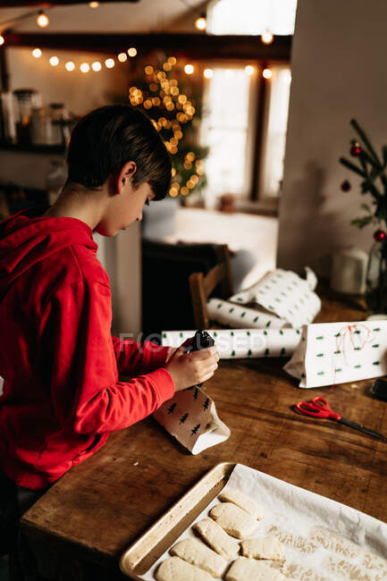 Boy wrapping shortbread cookies ready to be gifted  at Christmas — Stock Photo
