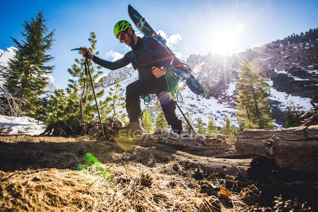 Baixo ângulo de homem andando em montanhas com esquis na mochila — Fotografia de Stock