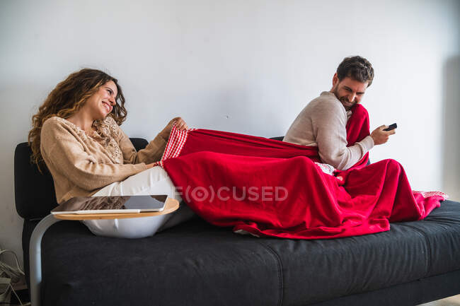 Glückliches Paar kämpft um Decke — Stockfoto
