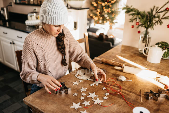 Young woman sitting at table creating star ornaments with clay — Stock Photo