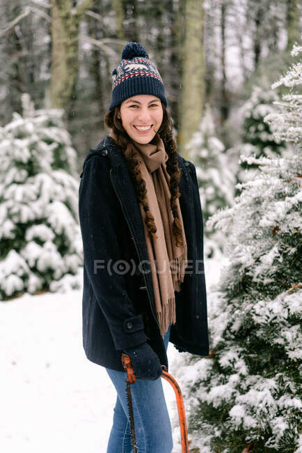 Портрет улыбающейся молодой женщины в мохнатой шляпе в снегу — стоковое фото