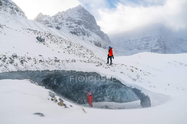Couple explorant une grotte de glace gelée dans un glacier — Photo de stock