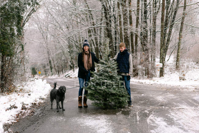 Jovem mulher, jovem e seu cão na fazenda árvore de Natal — Fotografia de Stock
