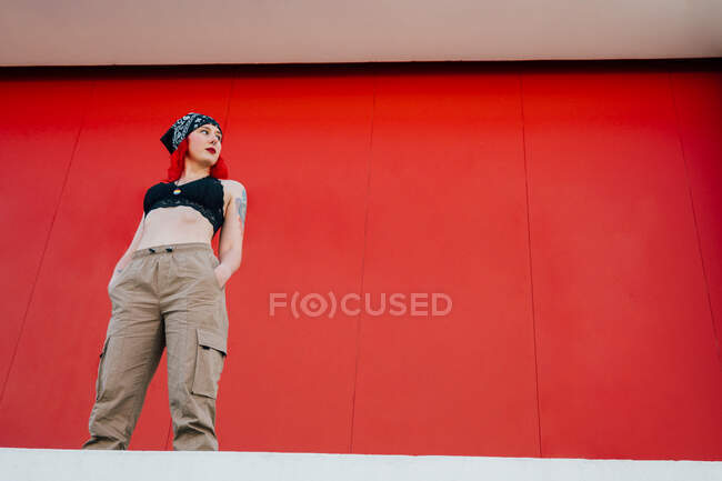 Menina com cabelo vermelho e um pingente lgbt em um fundo vermelho — Fotografia de Stock