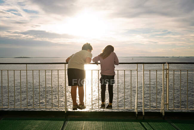 Garçon et fille avec des backs pour caméra regardant l'océan depuis un ferry — Photo de stock