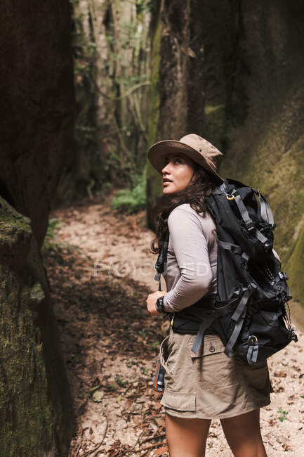 Jeune femme marchant dans un canyon avec sac à dos regardant en arrière. — Photo de stock