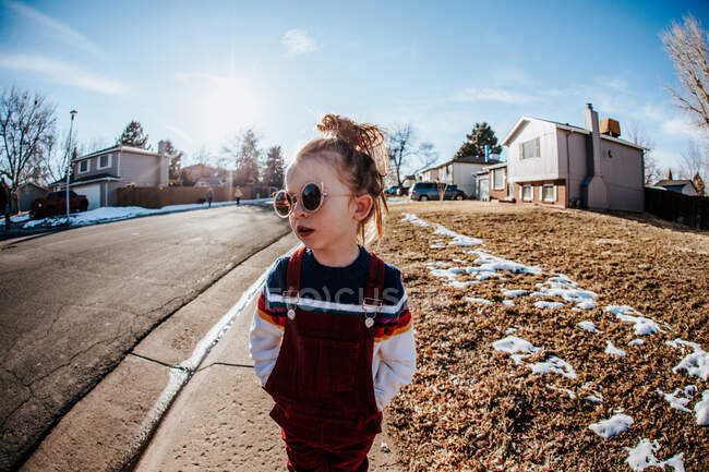 Young girl looking away standing on sidewalk in neighborhood — Stock Photo