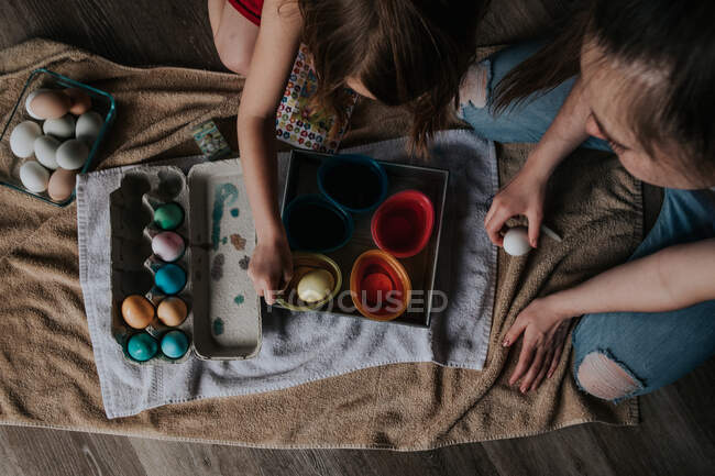 Overhead shot of sisters dying chicken eggs — Stock Photo
