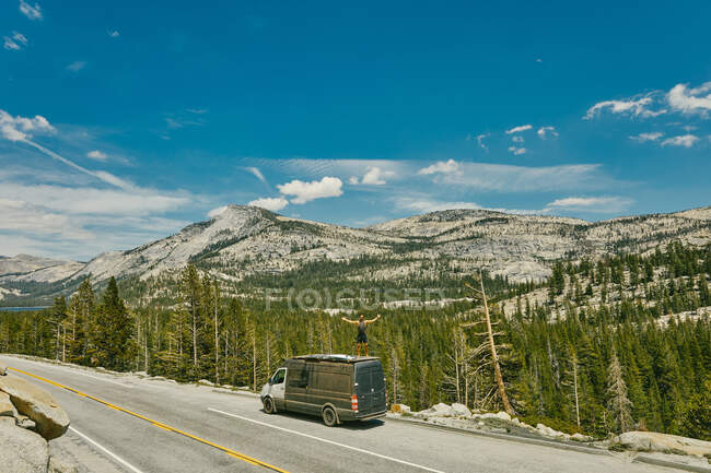 Young man standing on camper van watching views of Yosemite Park. — Stock Photo
