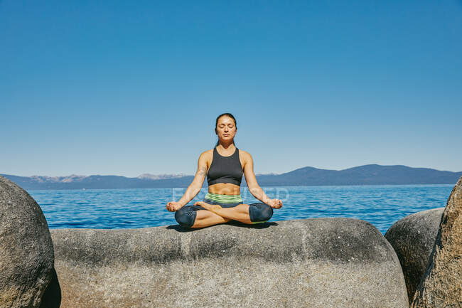 Young woman practicing yoga by the sea — Stock Photo