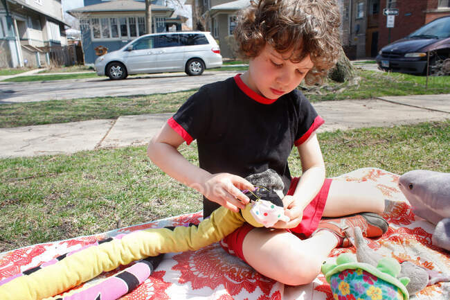 Un giovane ragazzo che fa maschere per i suoi animali di peluche — Foto stock