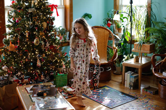 Une jeune fille regarde tous les cadeaux près du sapin de Noël — Photo de stock