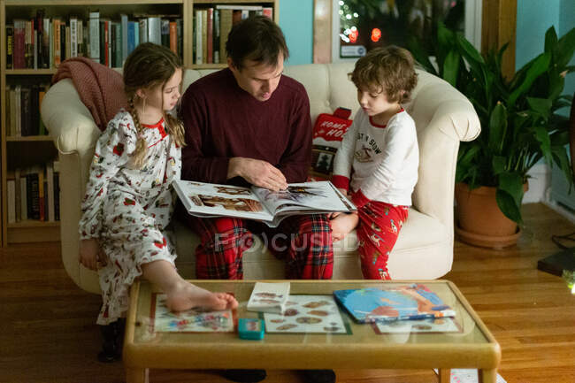 Vater liest seinen Kindern zu Weihnachten eine Gute-Nacht-Geschichte vor — Stockfoto