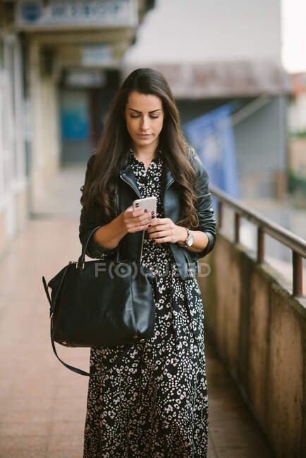 Donna che indossa abito sms sul telefono intelligente e passeggiando. — Foto stock