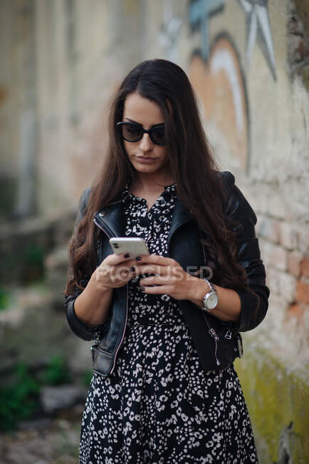 Attractive young woman looking at her phone outside and walking — Stock Photo