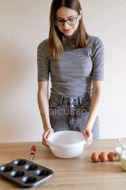 Donna in t-shirt e jeans preparare cupcake fatti in casa nella sua cucina — Foto stock
