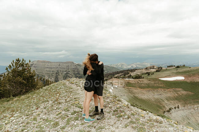 Couple engagé dans toute étreinte noire étreinte sur le sommet de la crête venteuse dans le wyoming — Photo de stock