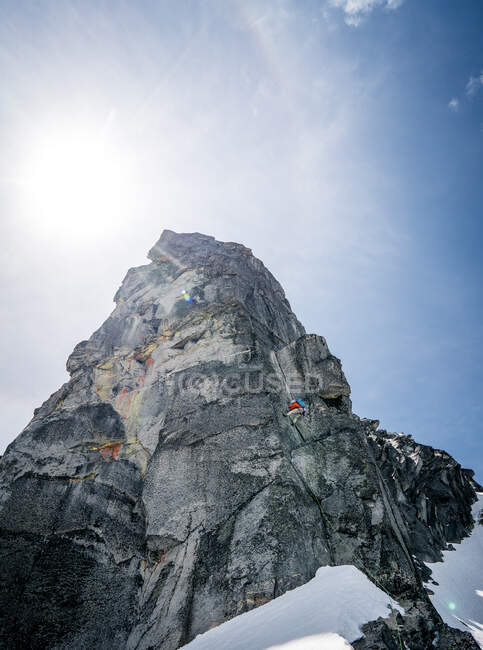 Male rock climbing giant peak in snow — Stock Photo