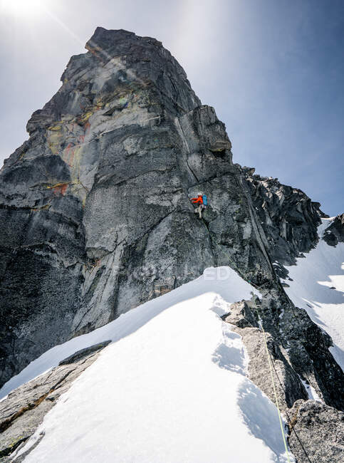 Male rock climbing giant peak in snow — Stock Photo