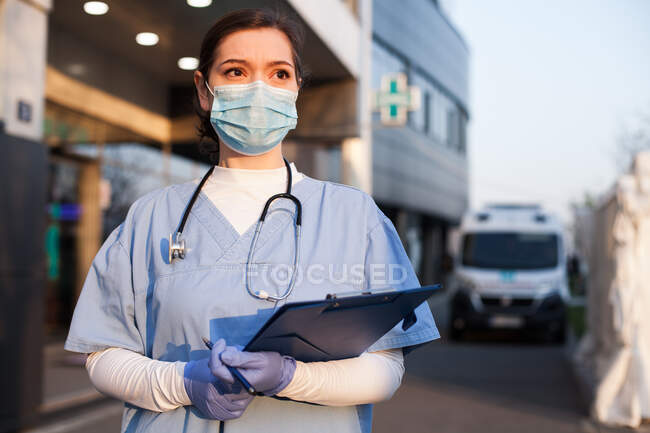Mujer joven EMS trabajador clave médico en frente de centro de cuidados intensivos de la salud - foto de stock