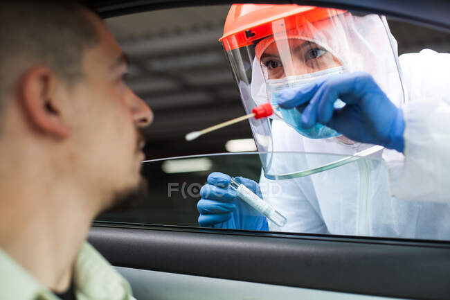 Medizinischer britischer NHS-Mitarbeiter führt Drive-Through-COVID-19-Test durch und nimmt Nasenspray ein — Stockfoto