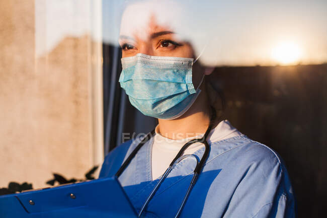 Young sad female caucasian UK US NHS EMS doctor carer looking through — Stock Photo