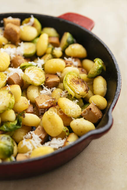 Gnocchi with Brussels sprouts and Vegan Hot Dog Pieces in a cast iron pan. — Stock Photo