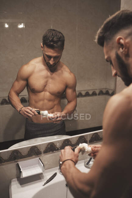 A strong boy is going to shave with a brush and razor — Stock Photo
