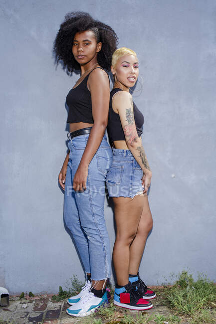 Дві однаково одягнені молоді жінки стоять спиною до спини разом — стокове фото