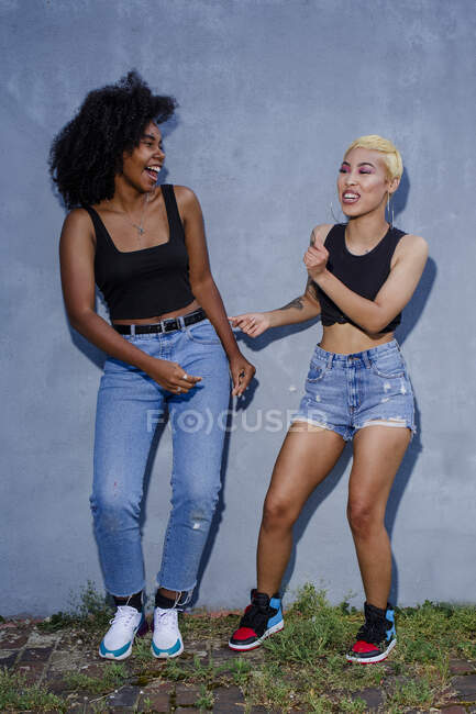 Dos amigos riendo en ropa a juego bailan juntos afuera - foto de stock