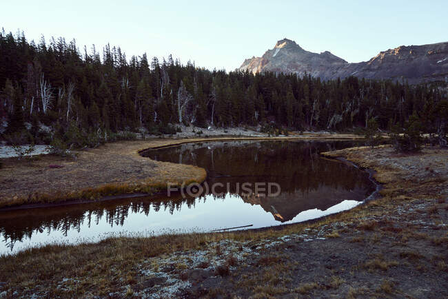 Reflection of mountain in winding creek — Stock Photo