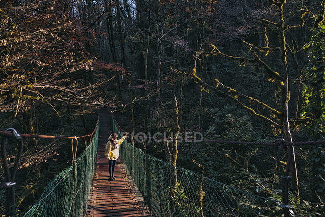 Mujer joven cruzando puente colgante - foto de stock