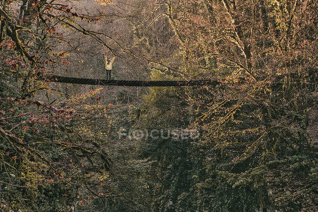Junge Frau auf Hängebrücke im Herbstwald — Stockfoto