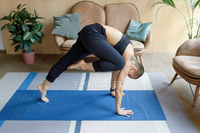 Atlética hembra haciendo yoga embestida ejercicio en acogedor hogar interior - foto de stock