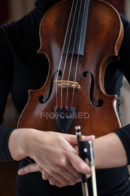 Female musician hands hugging violin near body in black dress — Stock Photo