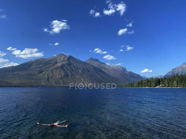 Un uomo galleggia sulla schiena nel McDonald Lake nel Glacier National Park, MT — Foto stock